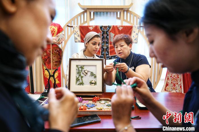 7月8日，嘉宾在“世界市长对话·上合峰会城市”主会场外设置的天津市级非遗代表性项目展上体验蜻蜓扣制作。记者 佟郁 摄